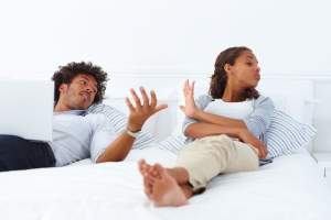 Portrait of a young unhappy African American couple lying on the bed and arguing